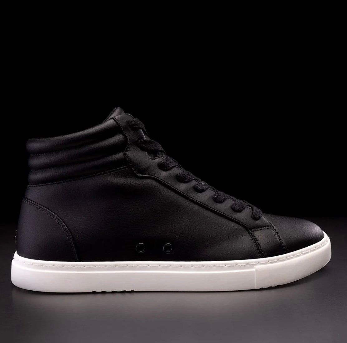 A black high-top sneaker with a white sole and black shoe lace