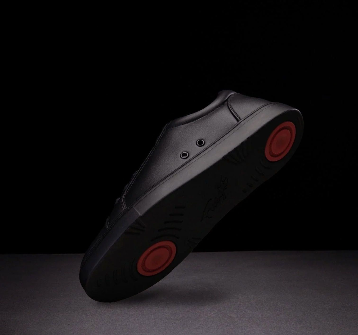 An all-black dance sneaker with red dual pivot points - angle view